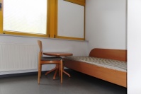Einzelbett und Stuhl Kernbuche-Optik WG-Zimmer, gelbe Fensterrahmen mit Jalousien
