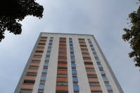 Saniertes, quadratisches Hochhaus mit 16 Etagen. Weiße Fassade mit Farbakzenten in blau und orange.