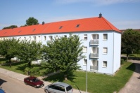 Häuserzeile mit neuer Fassade in hellem Blauton, Dächer neu. Bäume davor.