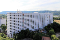 Über 140 Meter breites Hochhaus mit 15 Etagen,  weiße Fassade mit Farbelementen an Loggien. 