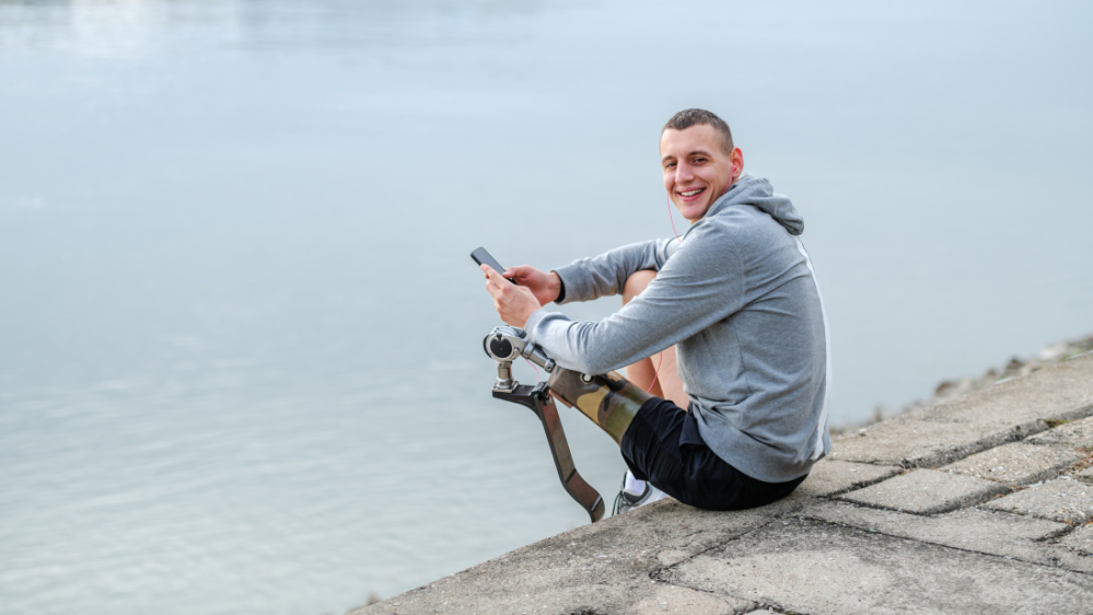 Ein Mann mit Protese lächelt und hält ein Handy Ein Mann mit Protese lächelt und hält ein Handy