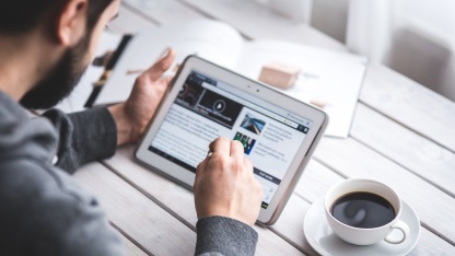  Mann liest Nachrichten auf Tablet-Computer