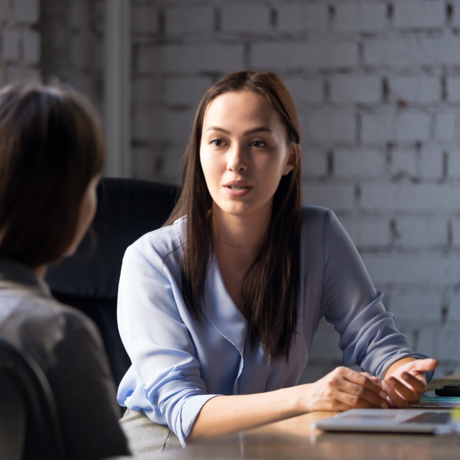 Dame berät Person - sitzend an einem Tisch