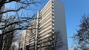 Hochhaus mit 15 Etagen, helle Fassade, Laubengänge. Haus ist 140 Meter lang. Vorne Gehweg, Straße, Bäume im Winter in der Morgensonne. Hochhaus mit 15 Etagen, helle Fassade, Laubengänge. Haus ist 140 Meter lang. Vorne Gehweg, Straße, Bäume im Winter in der Morgensonne.