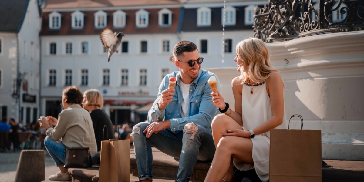 Shopping im Sommer Paar isst Eis während es am Marktbrunnen sitzt