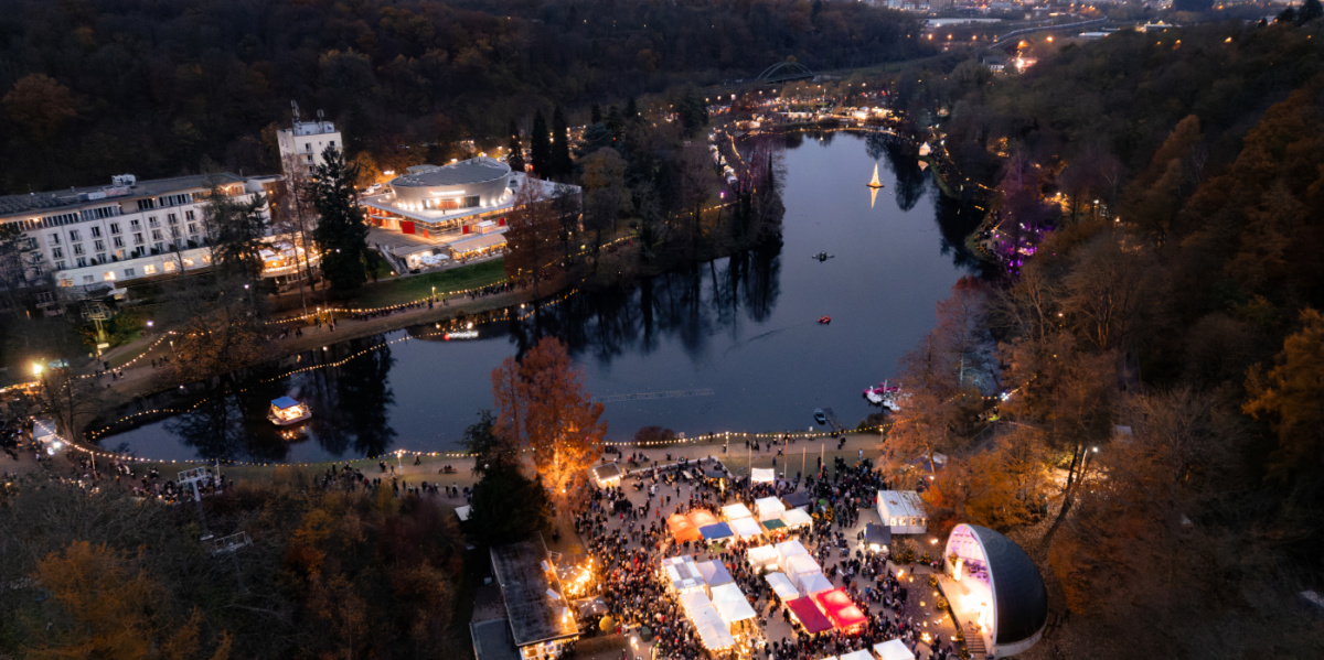 Blick von oben auf den Deutschmühlenweiher mit beleuchteten Ständen und der Seebühne