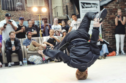 Man tanzt vor Leuten. Banner unten mit "QuattroPole Projektaufruf" geschrieben