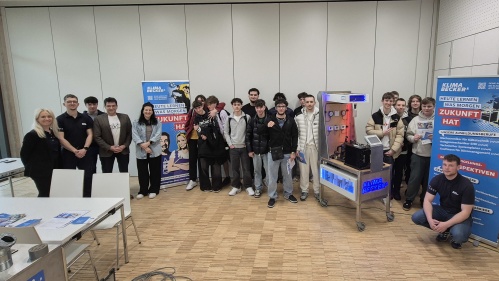 Eine Gruppe junger Menschen neben Geräten und Plakaten der Firma Klima Becker