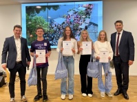 Ein junger Sportler mit einer Behinderung und drei junge Sportlerinnen zeigen ihre Ehrenurkunde. Links und rechts stehen zwei Männer mit Anzügen