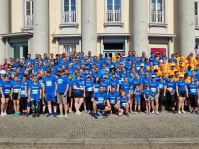 Eine große Gruppe von sportlich gekleideten Menschen posiert auf einer Treppe für die Kamera