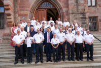 Eine größere Gruppe Feuerwehrleute posiert in ihrer Festuniform auf einer Treppe