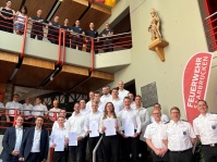 Angehende Feuerwehr Brandmeister posieren für ein Foto in einer Feuerwehrleitstelle