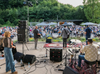 Man sieht die Rückseite einer Band und das zugewandte Publikum