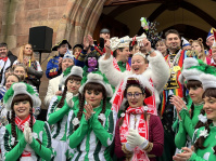 Eine große Menschenmenge in verschiedenen Kostümen versammelt sich auf den Treppen vor der Fassade des Saarbrücker Rathauses.