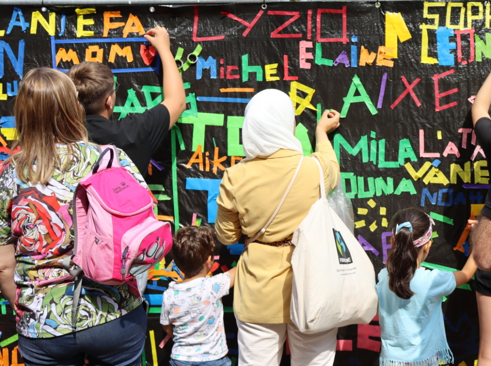 Kinderfest 2025 Personen bekleben eine schwarze Wand mit buntem Tape